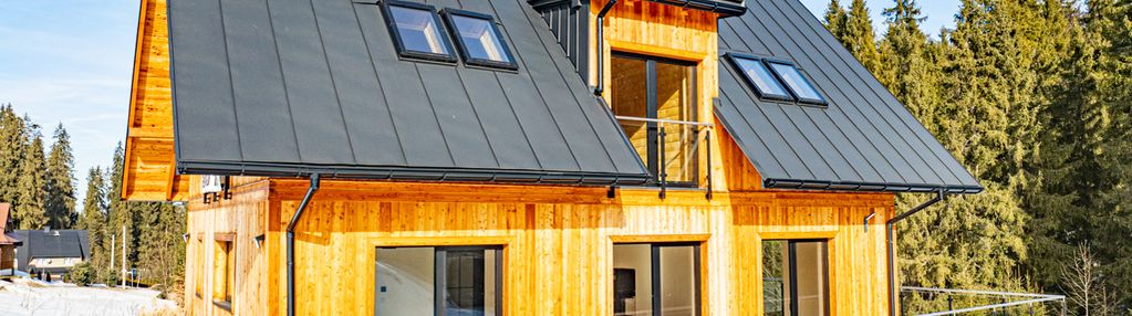 Dom jednorodziny z wiatą w otoczeniu lasu i potoku