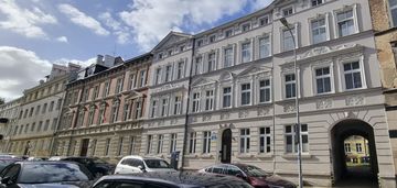 W kamienicy z zrobioną elewacją i dachem.