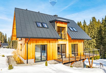 Dom jednorodziny z wiatą w otoczeniu lasu i potoku